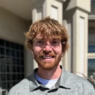 Licensed Massage Therapist Dylan Smling In Front Of Building